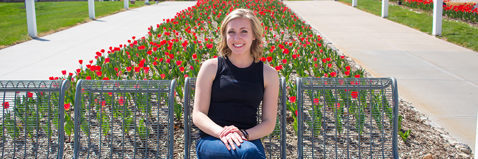 Annika Svoboda sits in front of some tulips on campus