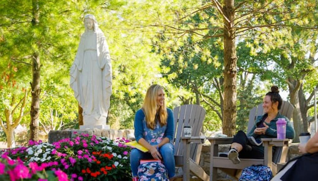 Three students in front of the Mary statue on campus